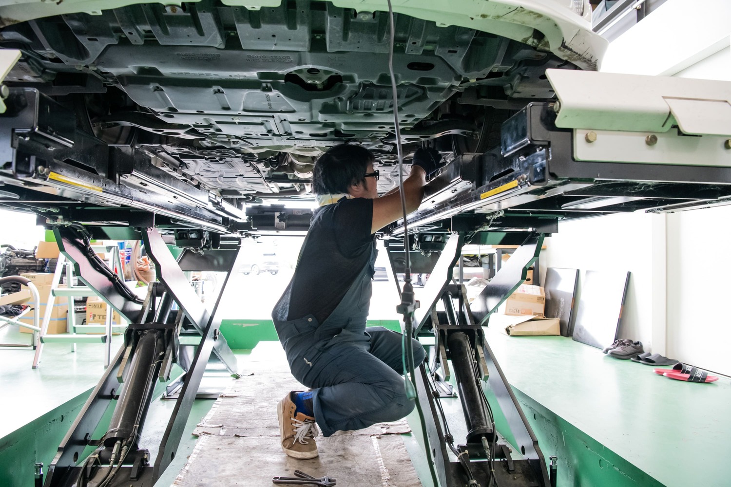 車両の下で作業する整備士の横姿