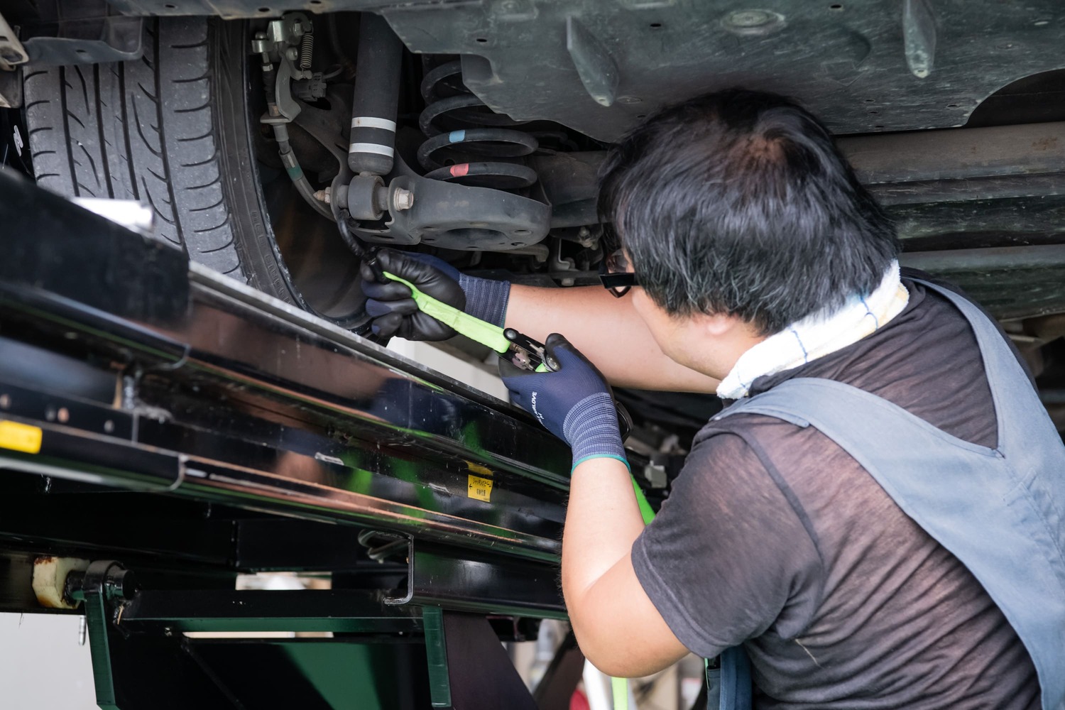 車のタイヤ部分を丁寧にメンテナンスする整備士