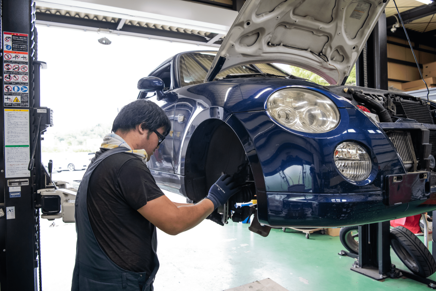 車のタイヤ部分を丁寧にメンテナンスする整備士